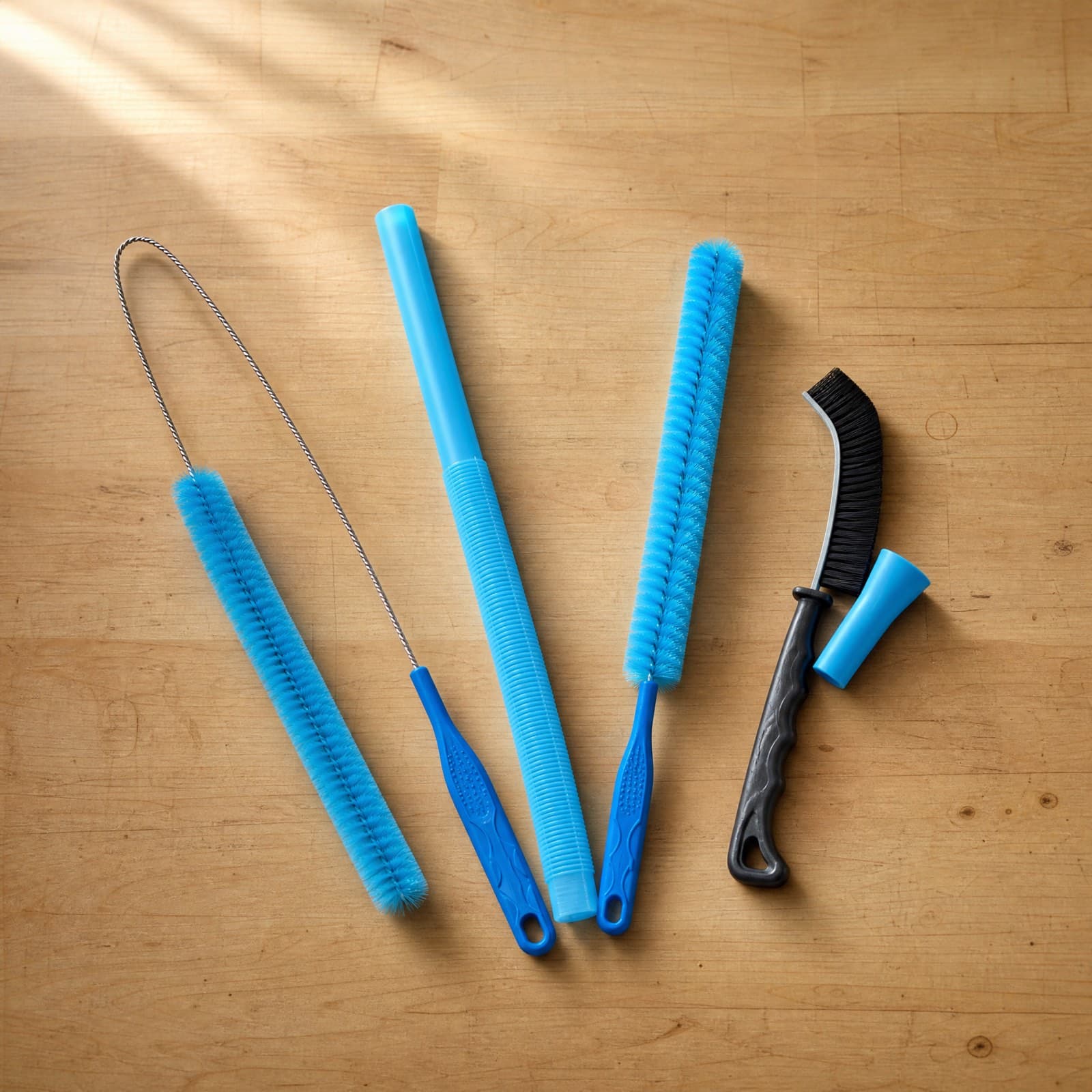 Flat vacuum hose, two long brushes, hand brush and stretch sleeve arranged on a wooden work surface